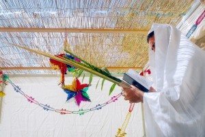 A Jewish man blesses on the four species in a Sukkah for the jewish holiday of Sukkoth.