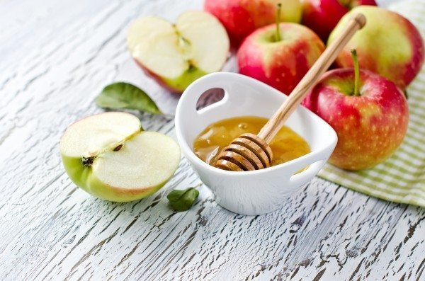 Apples with honey on white wooden background